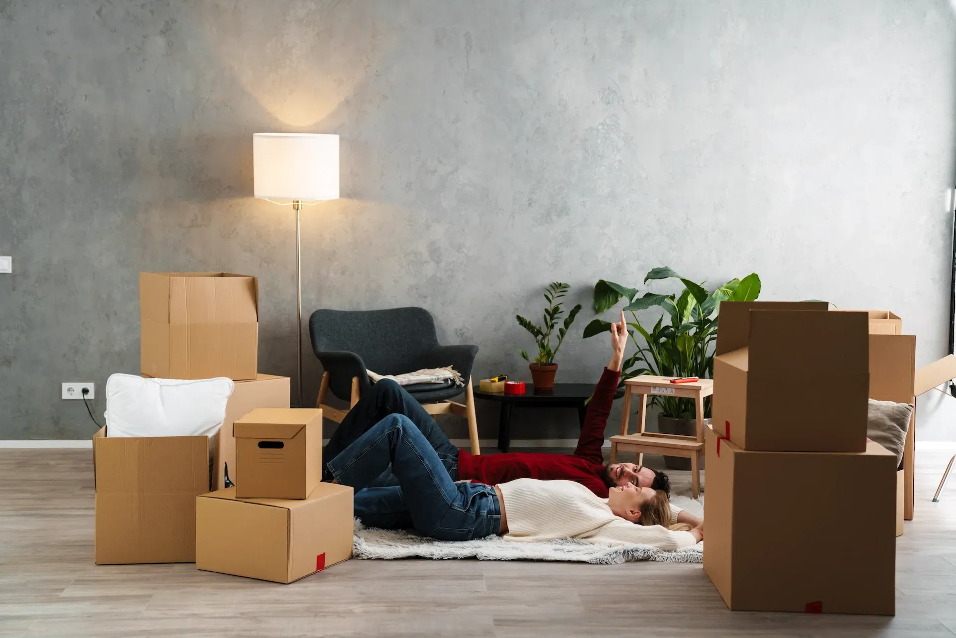 Couple relaxing on rug among moving boxes — settled in
