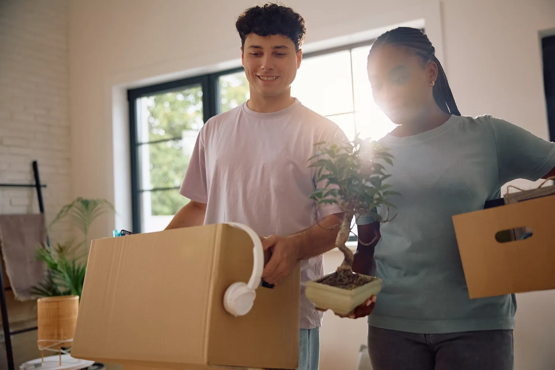 Young couple moving into a new home with a plant — settling in