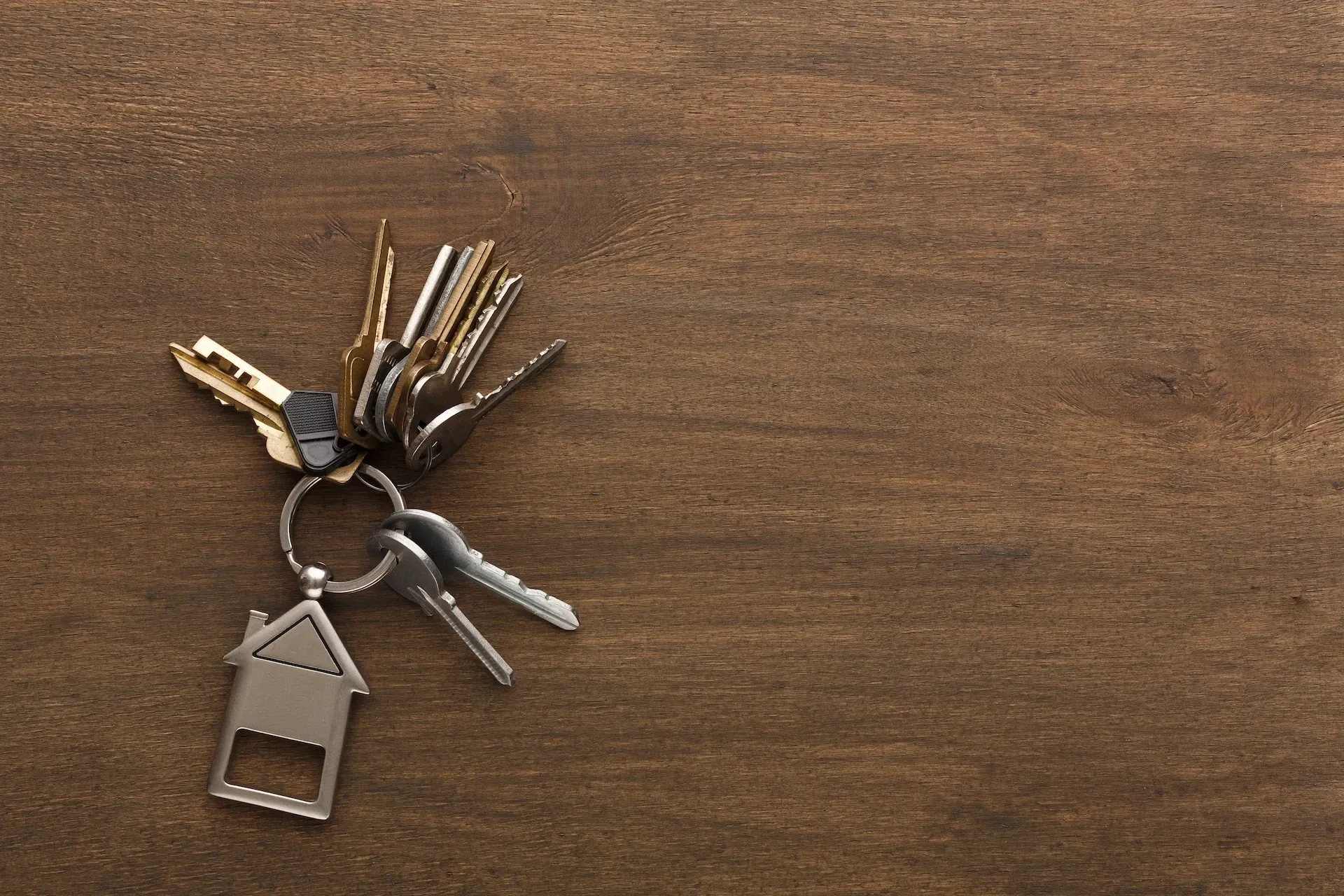 Keys and house keychain on a wooden table — real-estate motif