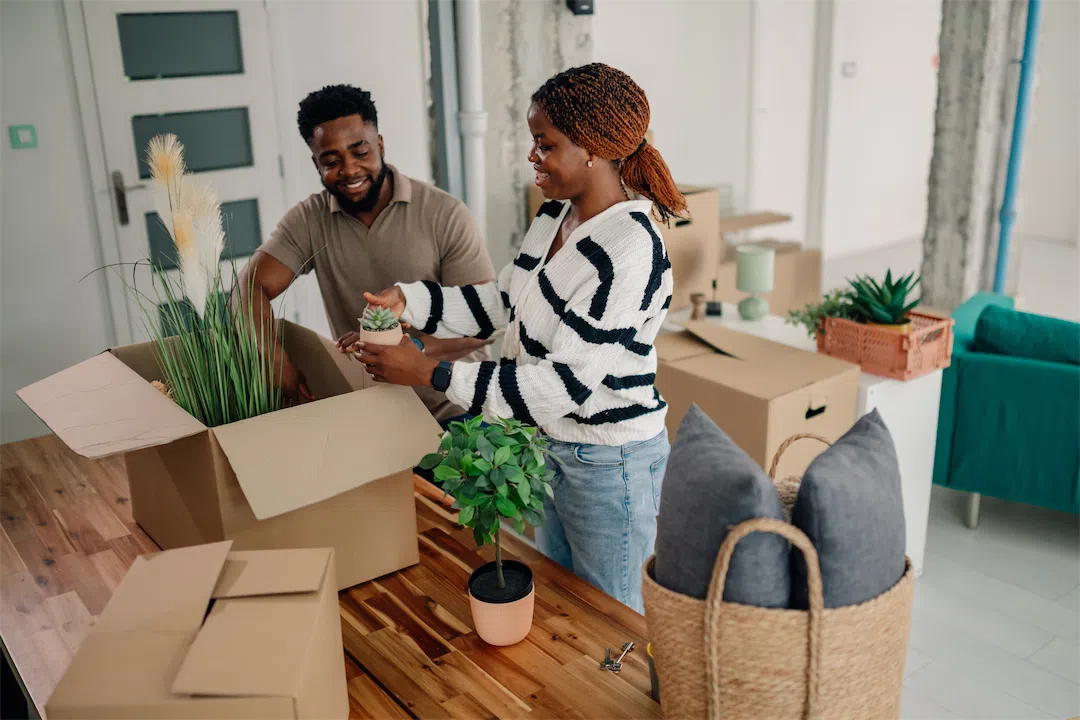 A happy couple unpacking plants in their new home after their offer was accepted.