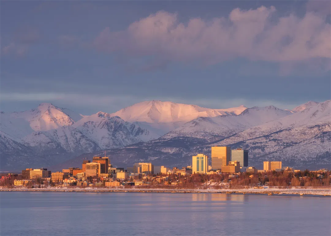 A scenic view of the Anchorage, Alaska skyline at golden hour, representing the local housing market.